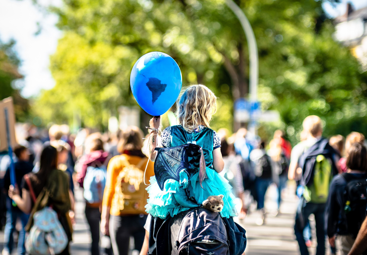 Kind auf den Schultern eines Erwachsenen  mit Luftballlon in der Hand